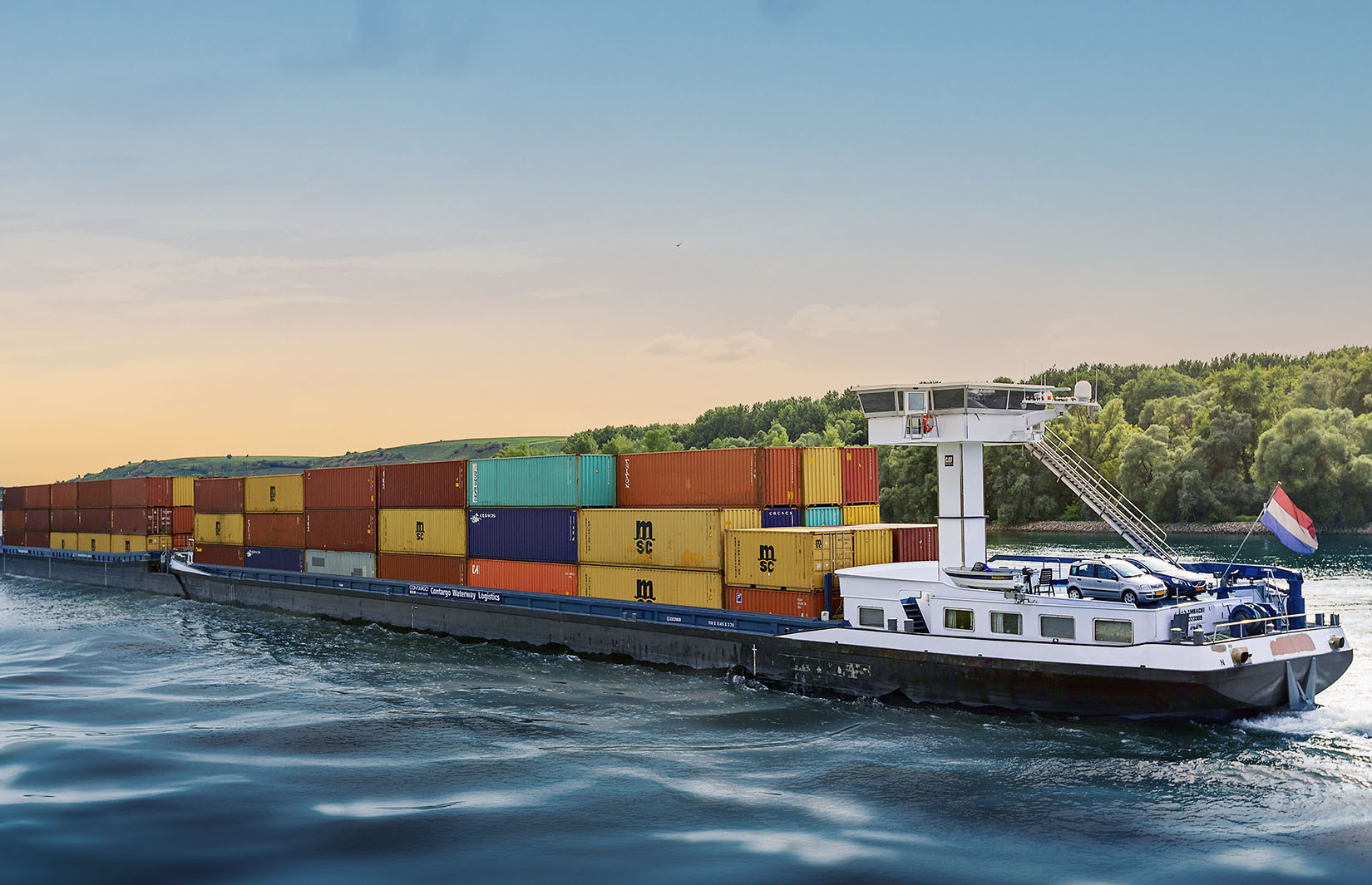 Binnenschiff mit gestapelten Containern auf Fluss