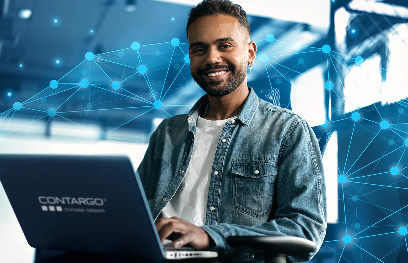 Entwickler arbeitet am Laptop und lächelt in die Kamera
