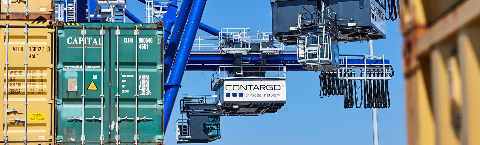 Links Containerstapel und im Hintergrund ein blauer Kran