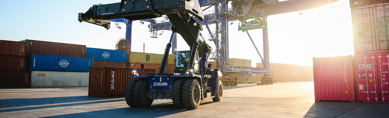 Reachstacker vor einem Kran auf dem Terminal