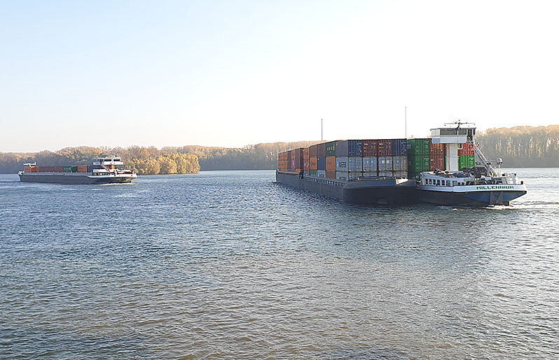 Binnenschiff mit Schubleichter auf einem Fluss mit weiterem Binnenschiff im Hintergrund