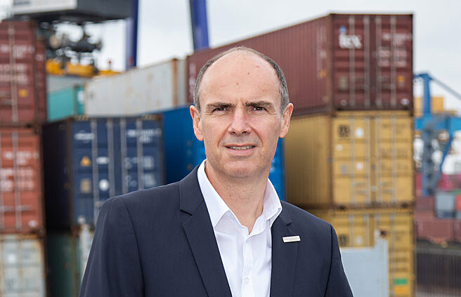 Portrait Jürgen Albersmann vor Containerstapel