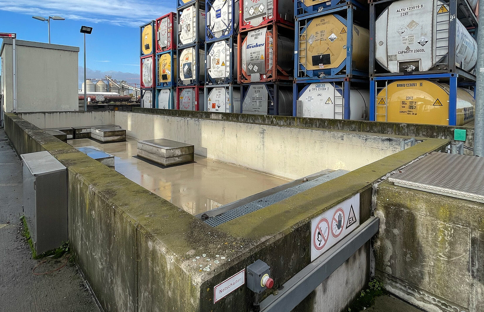 Leeres Gefahgut-Container Becken mit Tankcontainerstapel im Hintergrund