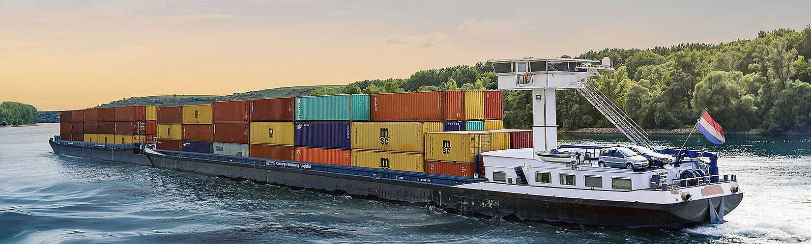 Binnenschiff beladen mit Containern auf einem Fluss