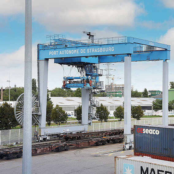 Blauer Container Kran. Darunter Zugschienen.