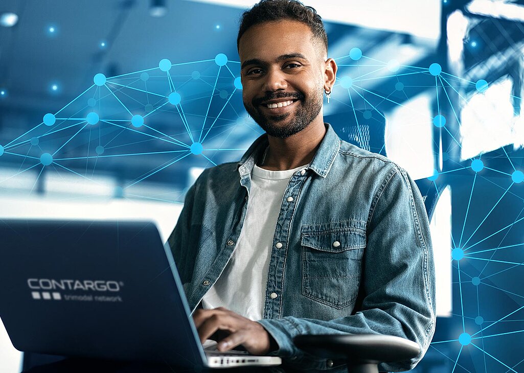 Entwickler arbeitet am Laptop und lächelt in die Kamera