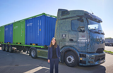 eActross E-Lkw mit blauen und grünen Containern und Kirstin Kahl am Terminal