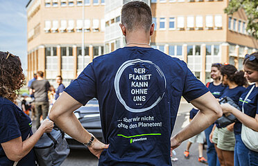 Mitarbeiter von hinten mit T-Shirt mit Aufdruck "Planet kann ohne uns, aber wir nicht ohne den Planeten"