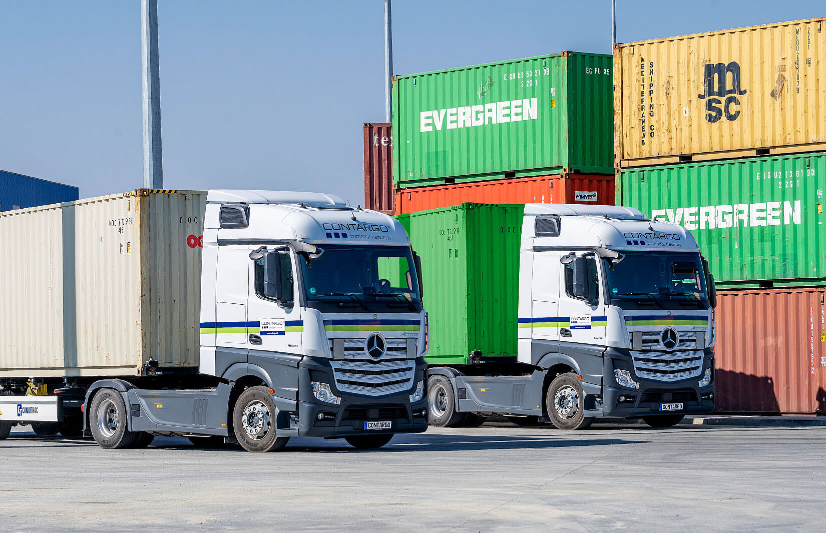 Zwei Contargo Lkw vor gestapelten Containern