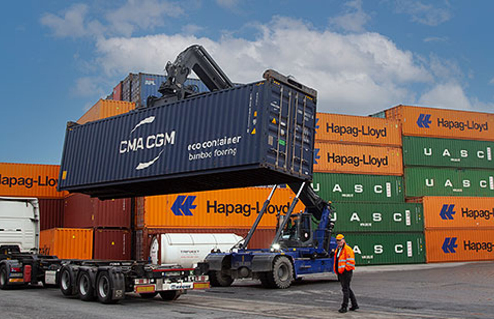 Container wird von einem Reachstacker auf einen Lkw geladen