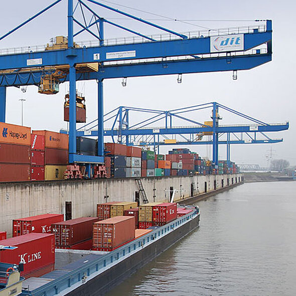Container-Terminal Duisburg mit Binnenschiff auf Fluss im Vordergrund und Kran im Hintergrund