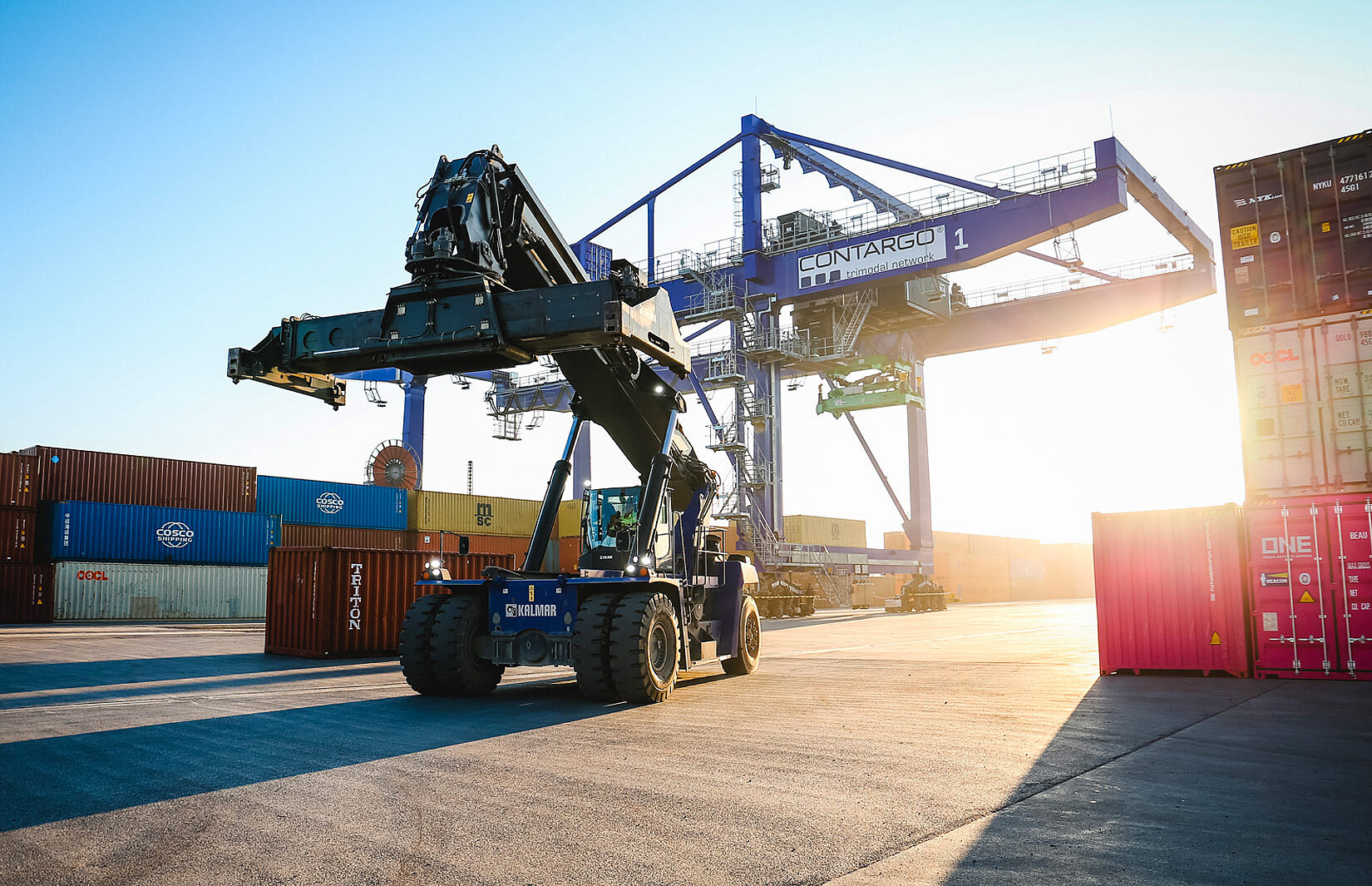 Reachstacker vor einem Kran auf dem Terminal