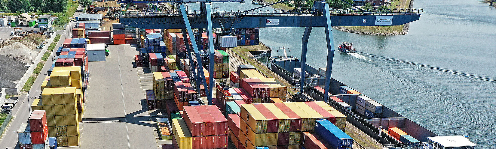 Container-Terminal mit Containerstapel und Krananlage am Fluss