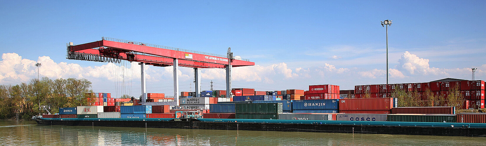 Beladenes Binnenschiff wird von Kran am Container-Terminal entladen