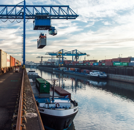 Eine Krananlage entlädt einen Container vom Container-Schiff auf einen Zug